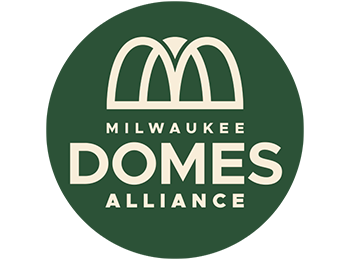 Green circle with tan logo and text. Logo has a triple overlapping arch icon indicating the shape of the Milwaukee Domes. Text reads "Milwaukee Domes Alliance"