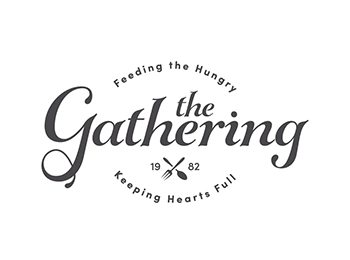 Logo for the Gathering, all elements in a warm gray color, featuring "the gathering" in scriptlike font in the center and sans serif text in an oval shape arcing above and below the center text. Above it reads "feeding the hungry" and below it reads "keeping hearts full." A small insignia of a crossed spoon and fork with the establishment date of 1982 is just below the middle text.